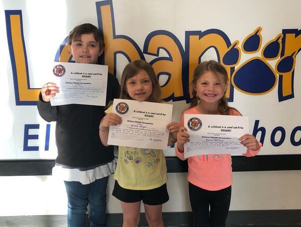 3 happy students showing awards