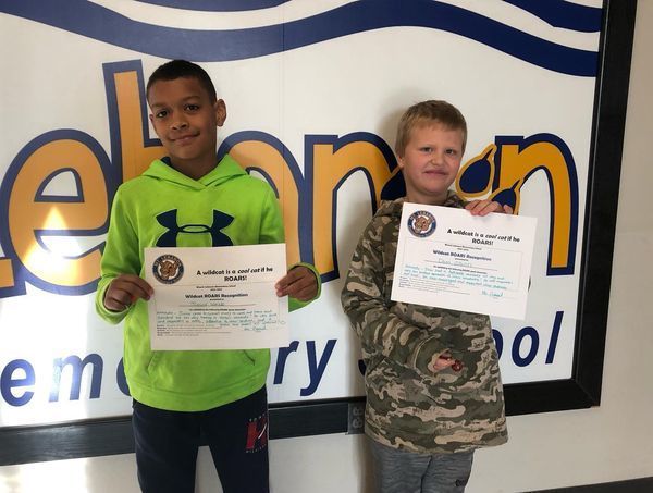 2 students excitedly showing award